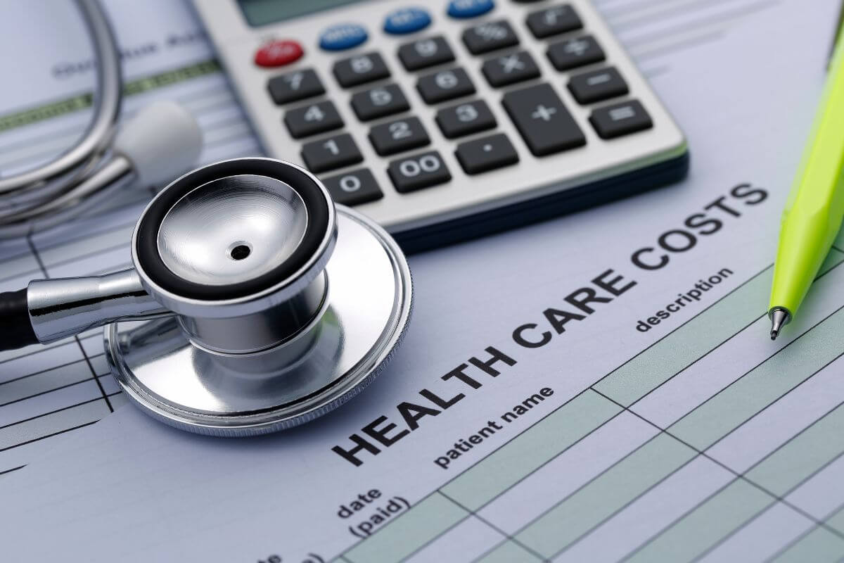 The photo tells about a pen, a stethoscope, a calculator, and a piece of paper with notes indicating  Medicare helps retirees lower healthcare costs making healthcare more affordable and reducing financial stress.