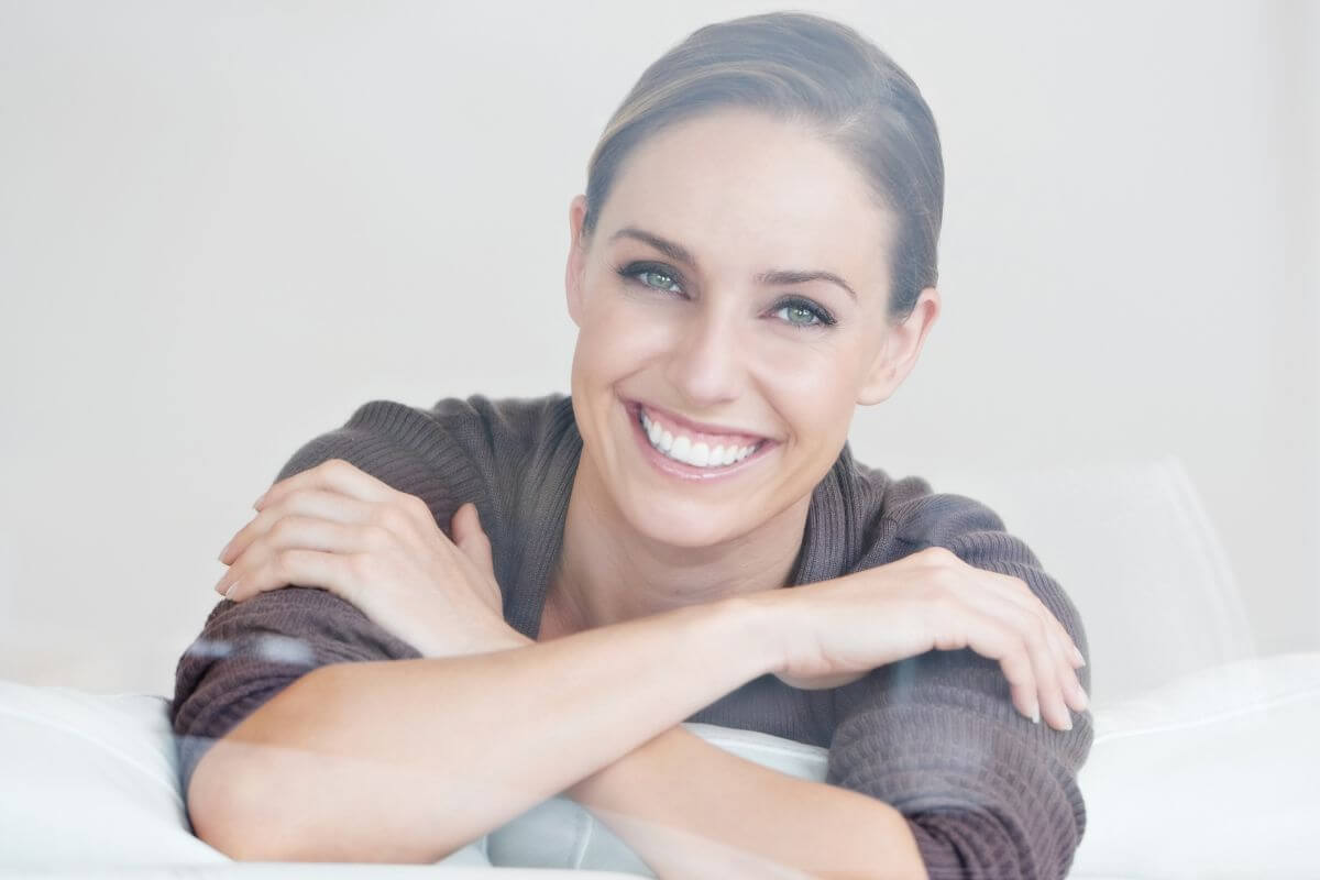 The image shows a girl smiling which means staying positive and patient while working toward long-term success helps you focus on the steps you need to build lasting wealth.
