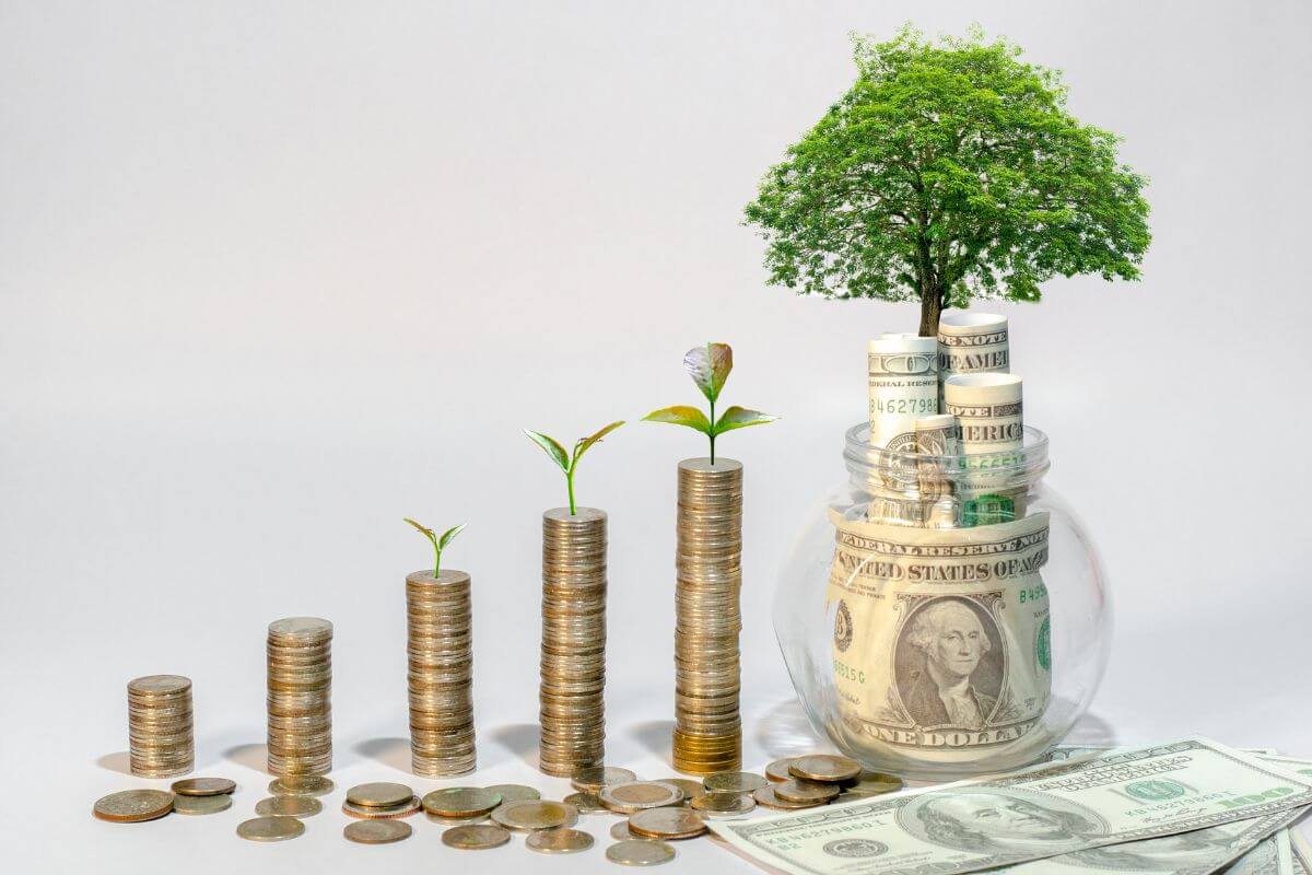 The image tells about coin stocks, dollar bills, jars with dollar bills, and with mini tree referring to how good debt can improve your financial future when done carefully.