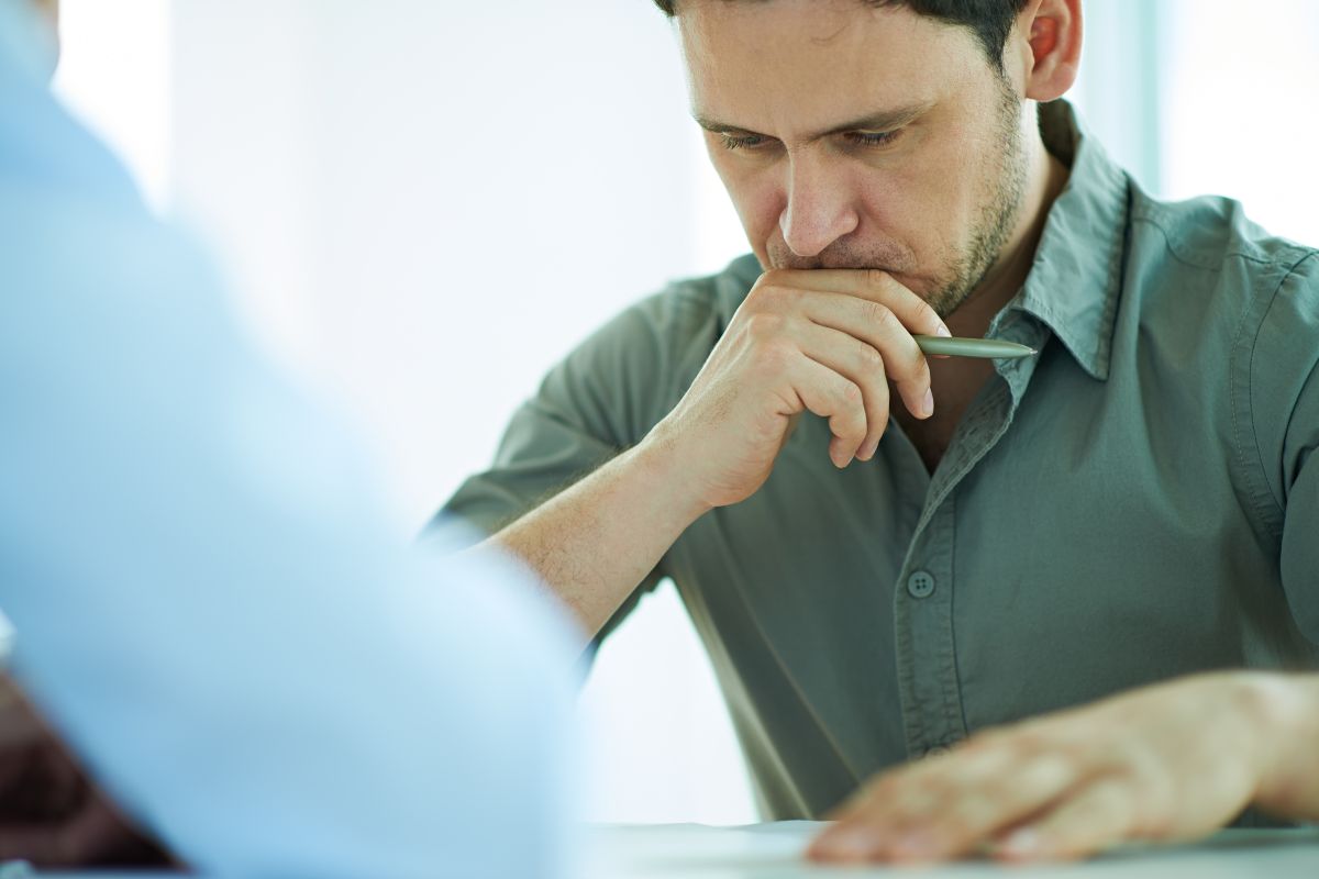 The image shows a man thinking deeply while looking at the paper which refers to being cautious about overextending even good debt can cause problems if you borrow more than you can handle.