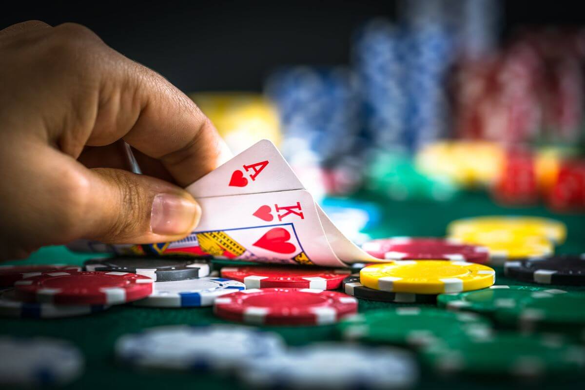 The photo tells about money coin chips and a man's hand holding cards indicating that gambling is not an investment strategy, instead focusing on building wealth with smart investment. 