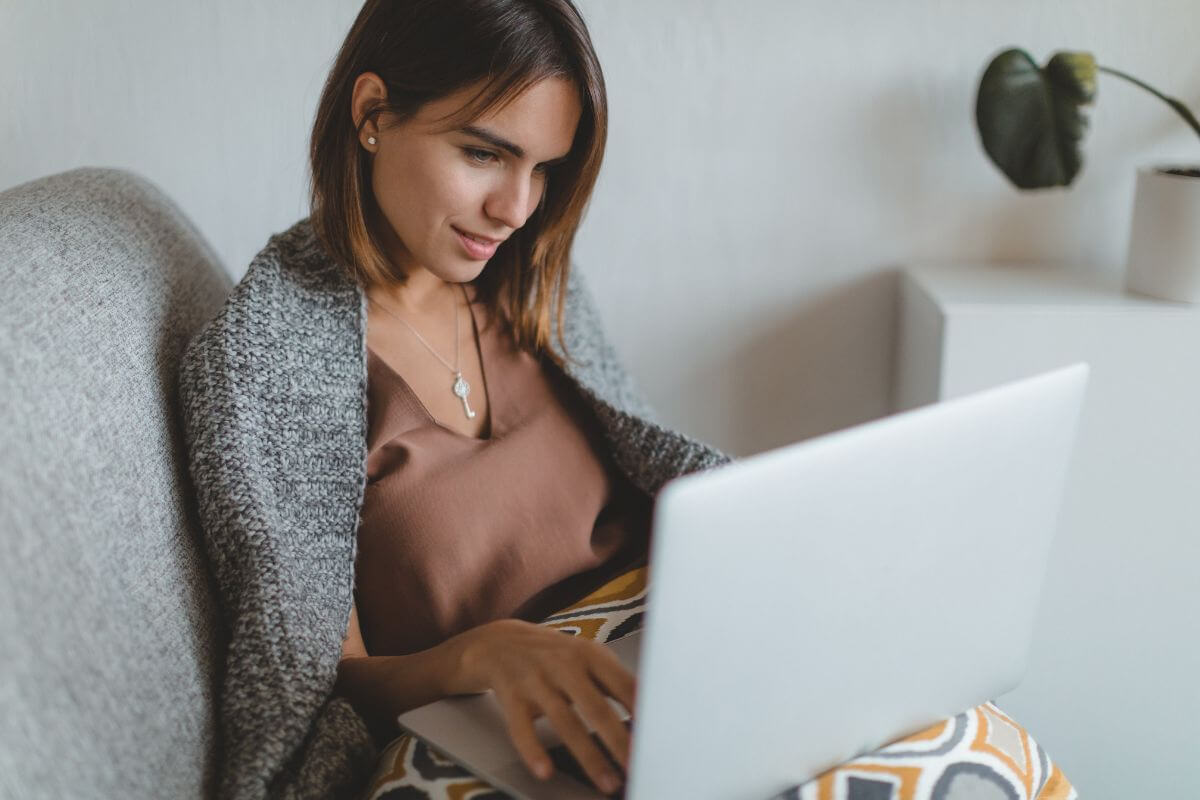 The picture shows a girl using a laptop referring to read the fine print before signing up and always check the details before committing.