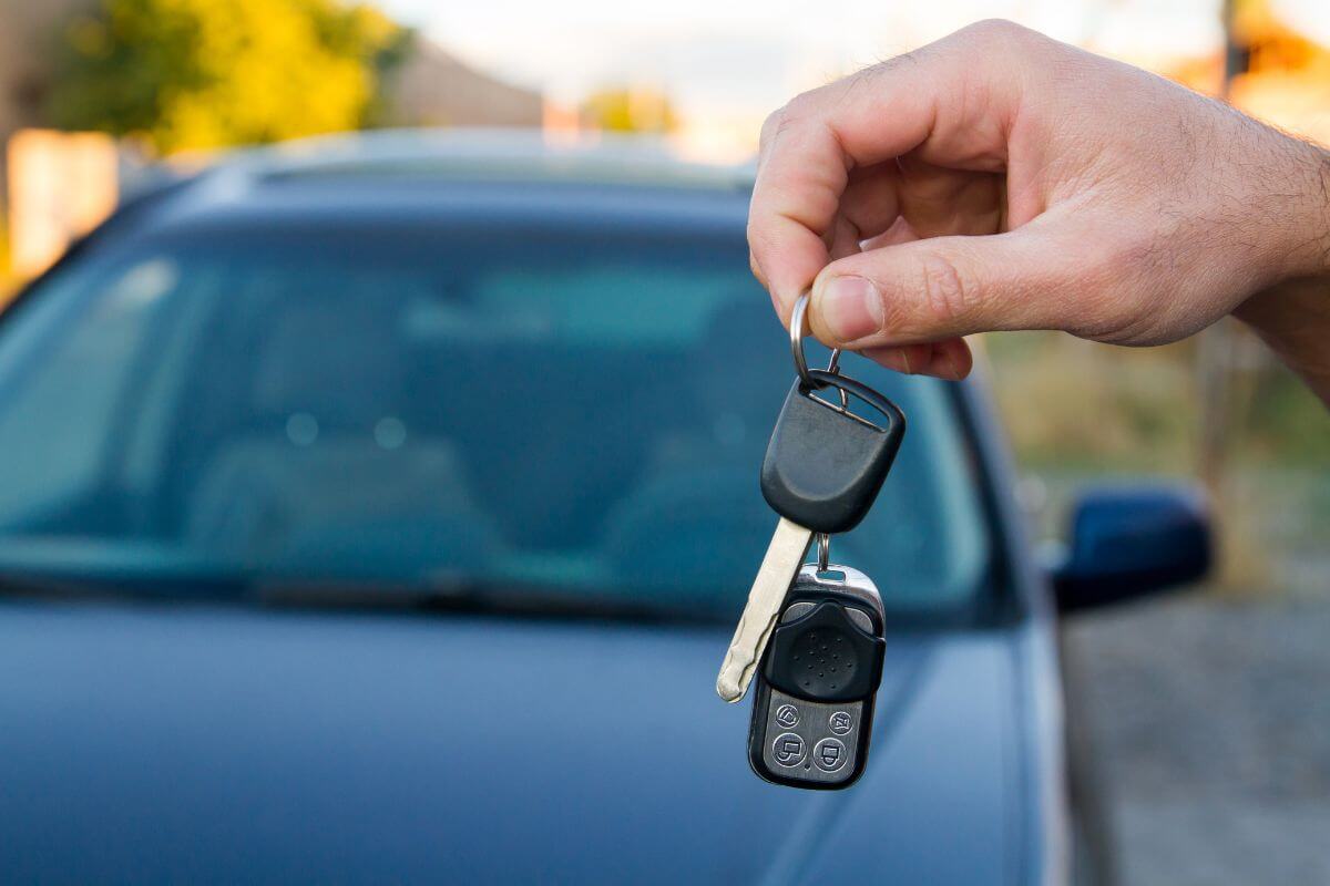 The image shows a car and a man's hand holding a key referring that you don't need to upgrade your car when yours still runs fire and save that money for more important goals.