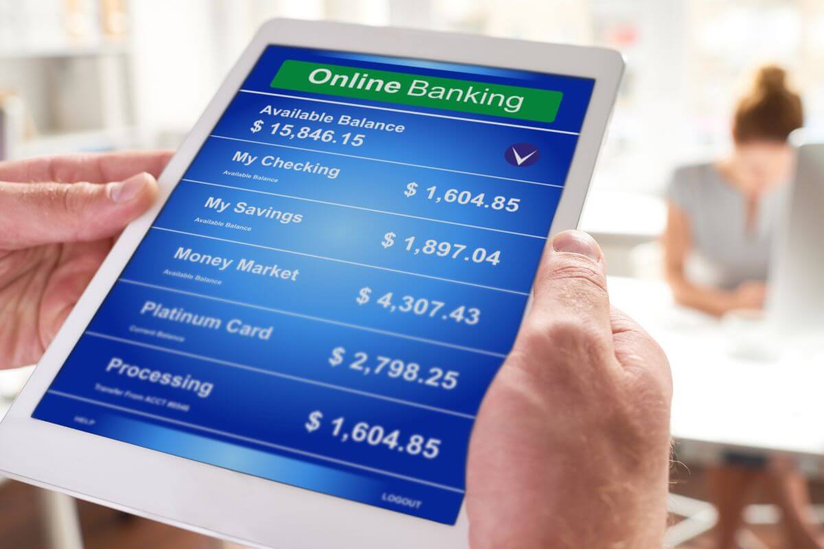 The image tells about a man's hand using a tablet device with a screen display and a girl behind which means to check your bank balance before making it rain so you can avoid overdrafts and stay on top of your bills.