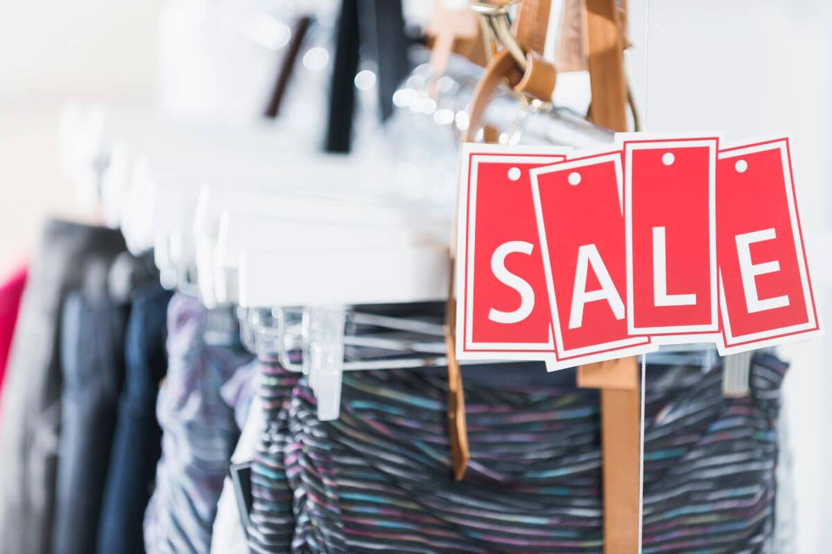 The photo of a rack with clothes tag shows that just because it's on sale doesn't mean you need it, focus on your budget and only buy essentials.
