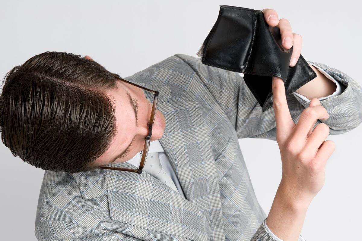 The picture tells about a man in a suit showing his empty wallet referring to stopping saying I am broke and working toward becoming financially sound.