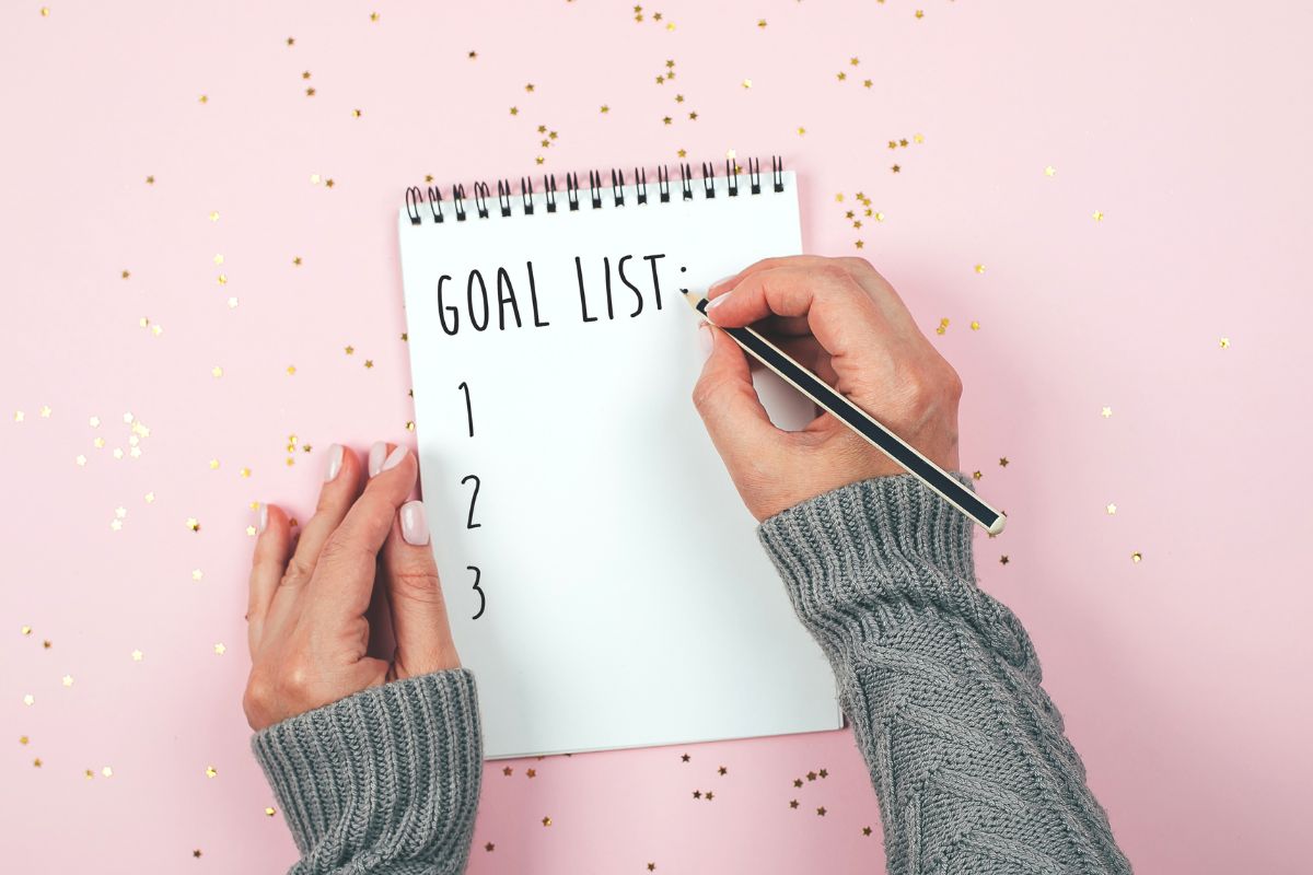 Photo of a woman's hand making a goal list.