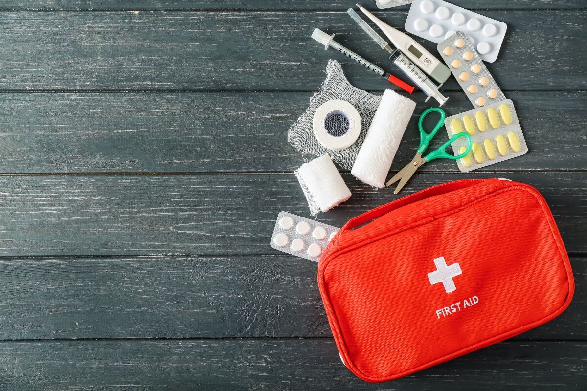 The image of a small pouch, medicines, scissor, syringe, and more on the table which refers to grab all medications and supplies so you have anything you need ready to go.