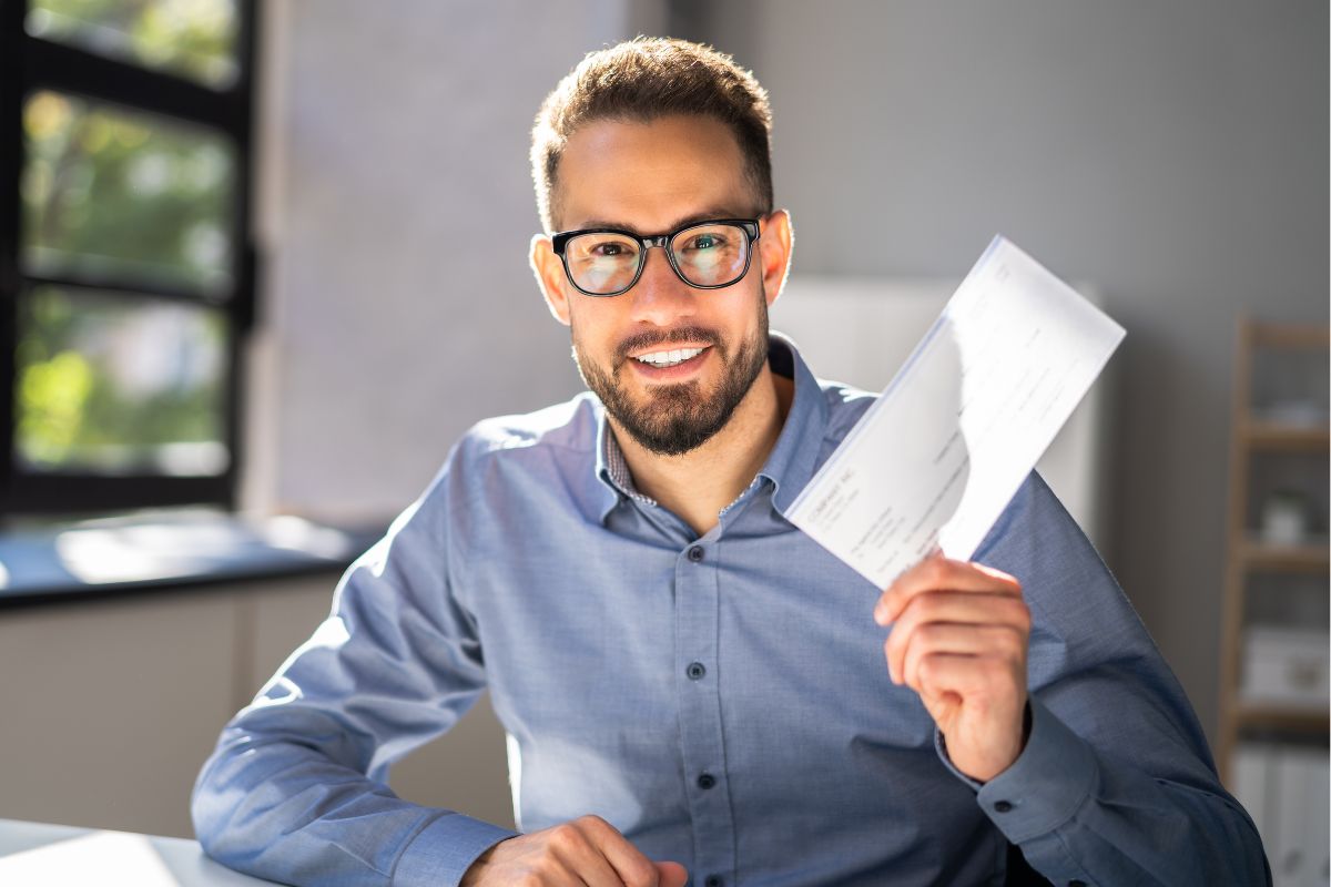 Image of a man holding a paycheck.