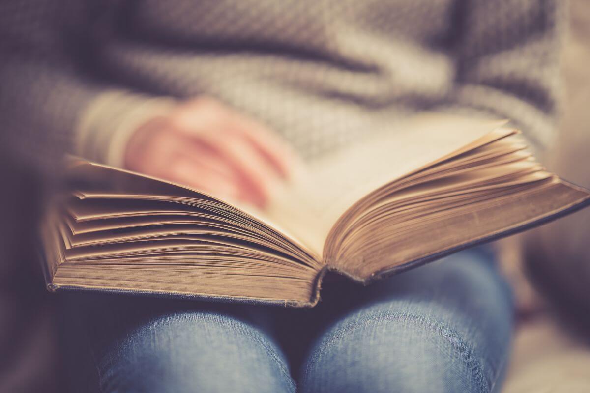 The picture tells about a girl reading a book titled How to Make Money In Stocks by Bill O'Neil perfect for those ready to start investing but unsure where to begin. 
