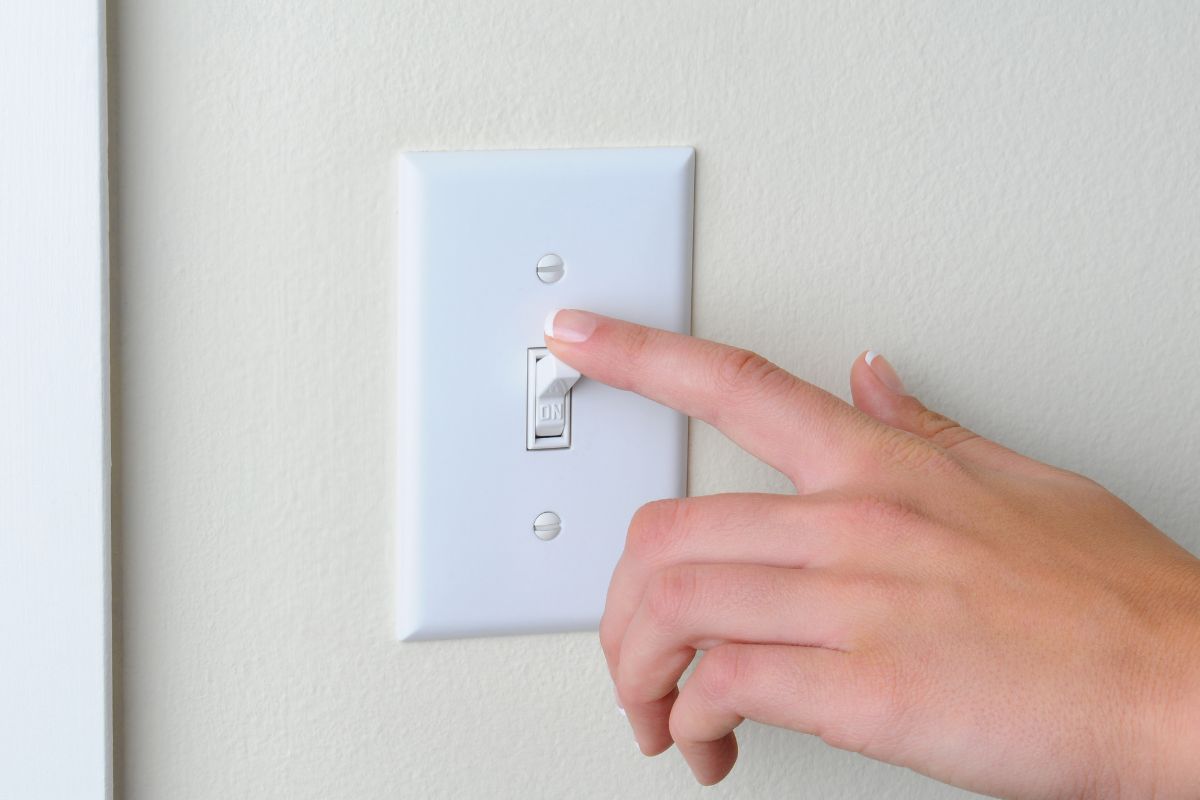 Photo of a woman's hand turning off a light switch.
