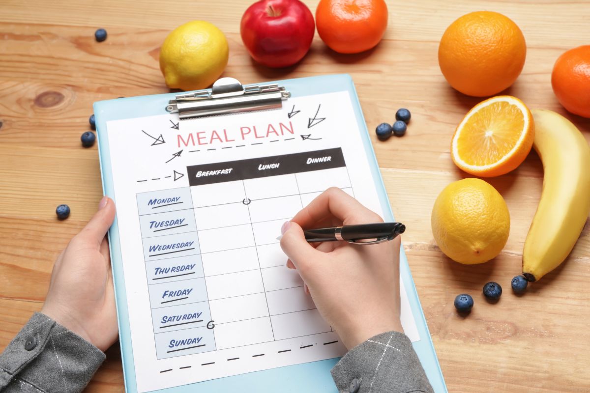 Image of a woman's hand making a meal plan.