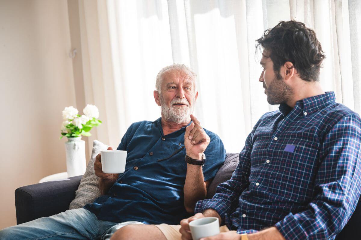 The photo of a senior talking to his son while having a coffee in the living room which means not discussing end-of-life wishes with family can lead to misunderstanding and disagreements. 