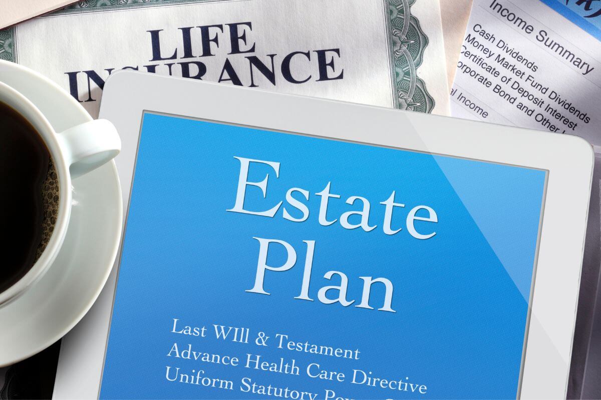 The image tells about paper with notes, a coffee, and a tablet device with a screen display referring to not updating estate plans after major life changes can make your old estate plan outdated and it could mean your assets go to the wrong people.