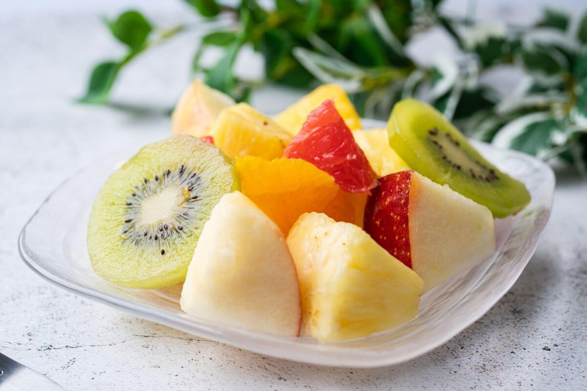 The photo tells about different varieties of fruits on a small plate on the table referring to pre-cut fruits can cost more and spoil faster, chopping it yourself can save money.