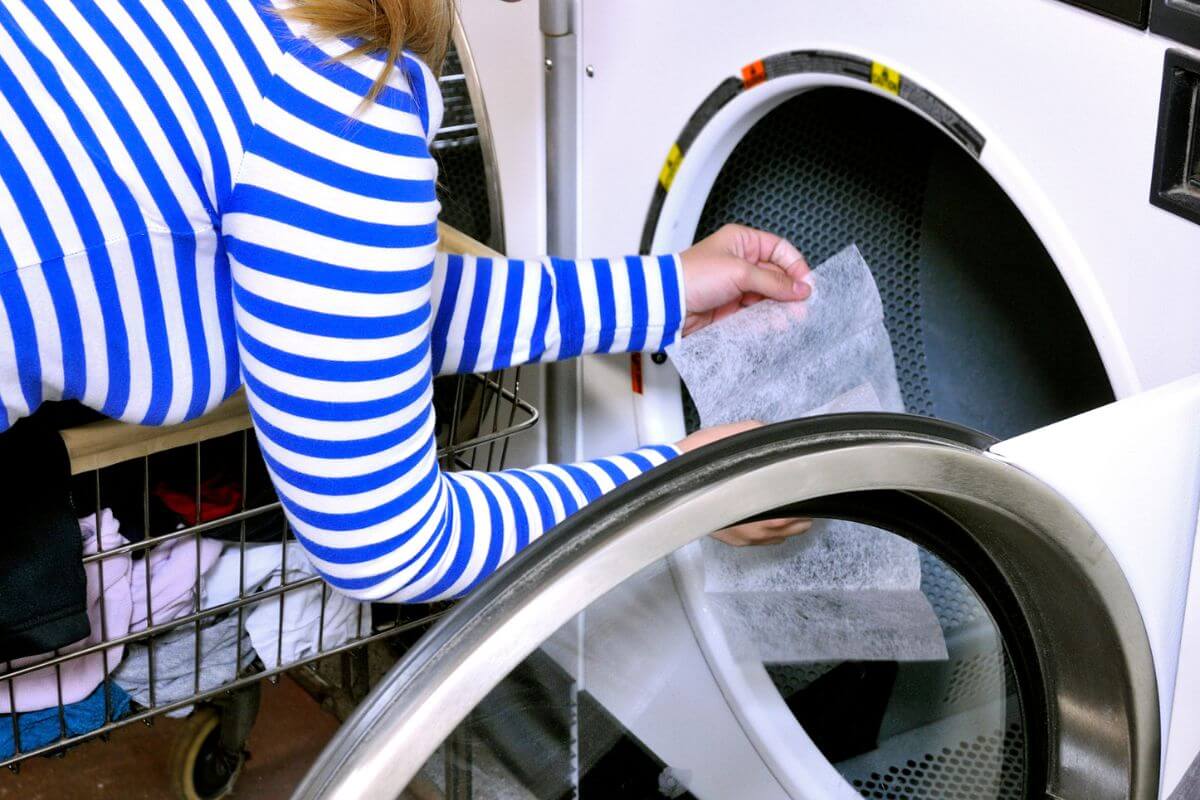 The image shows a girl's hand adding dryer sheets into the washing machine indicating to avoid buying it and use an alternatives like wool dryer balls to save money.