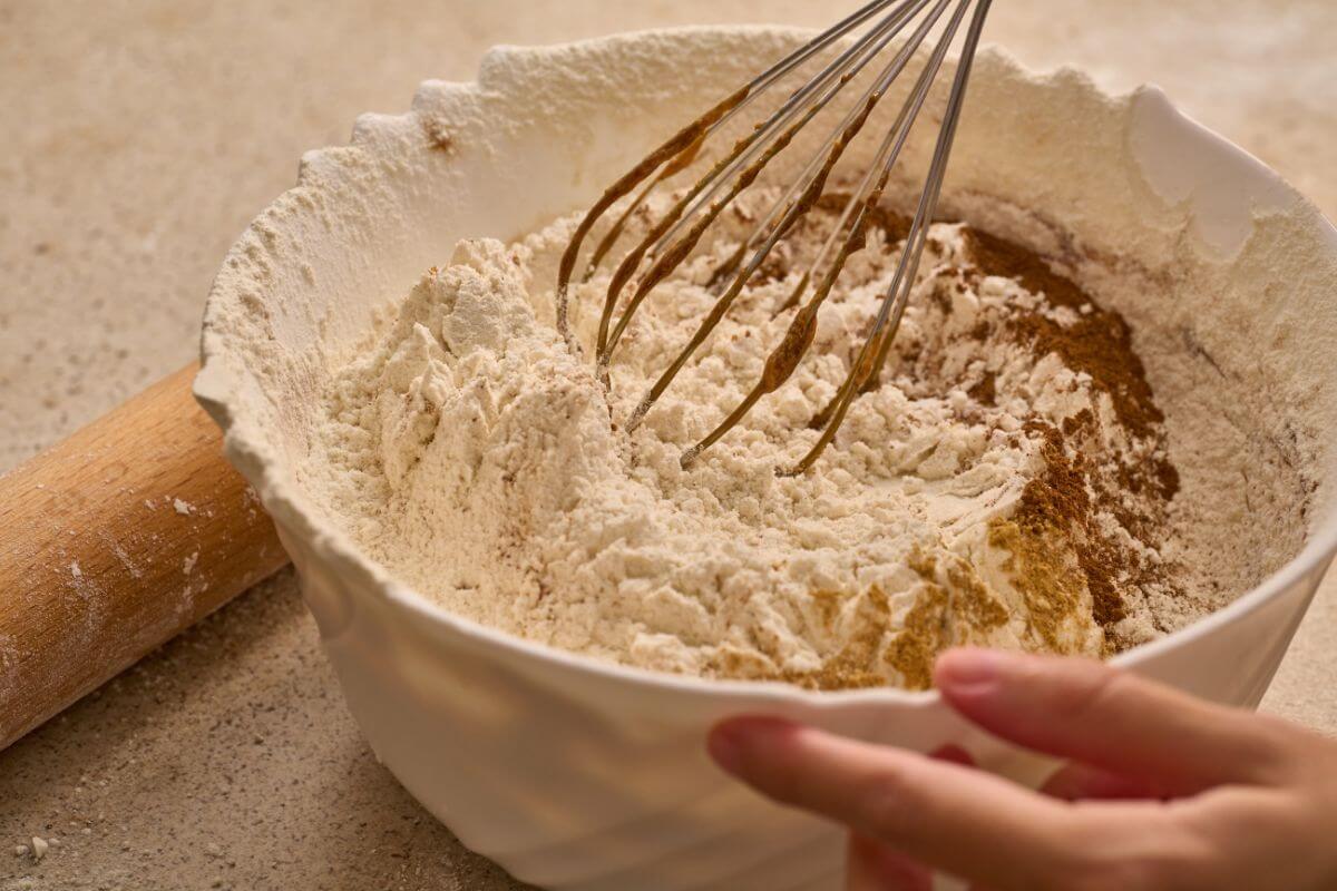 The image tells about a rolling pin and a girl's hand mixing dry ingredients in a bowl referring to specialty baking mixes for one recipe are more often expensive than making recipes from scratch.