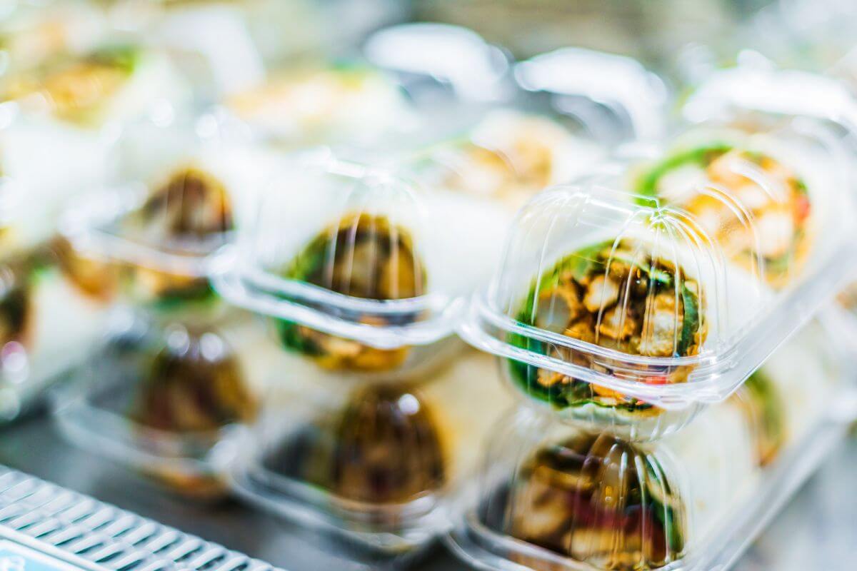 The image tells about packed sandwiches in a chiller referring to pre-made sandwiches that are often overpriced, buying the ingredients and assembling them yourself is much cheaper.