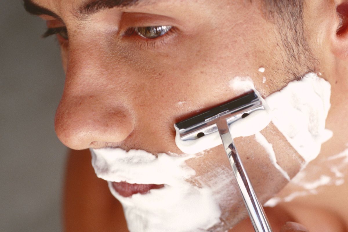 Photo of a man using a shaving cream.