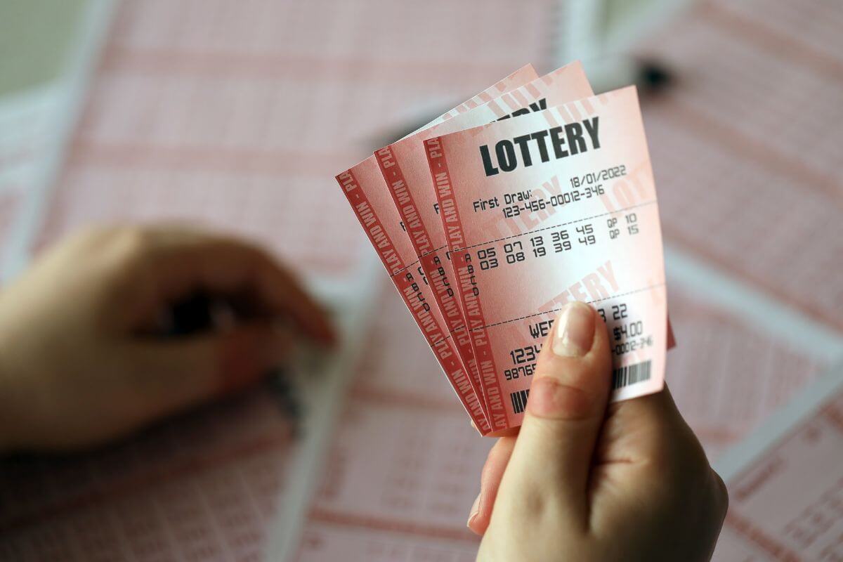 The picture tells about a girl's hand holding lotto tickets that will use your money and put the cash towards savings or debt instead.