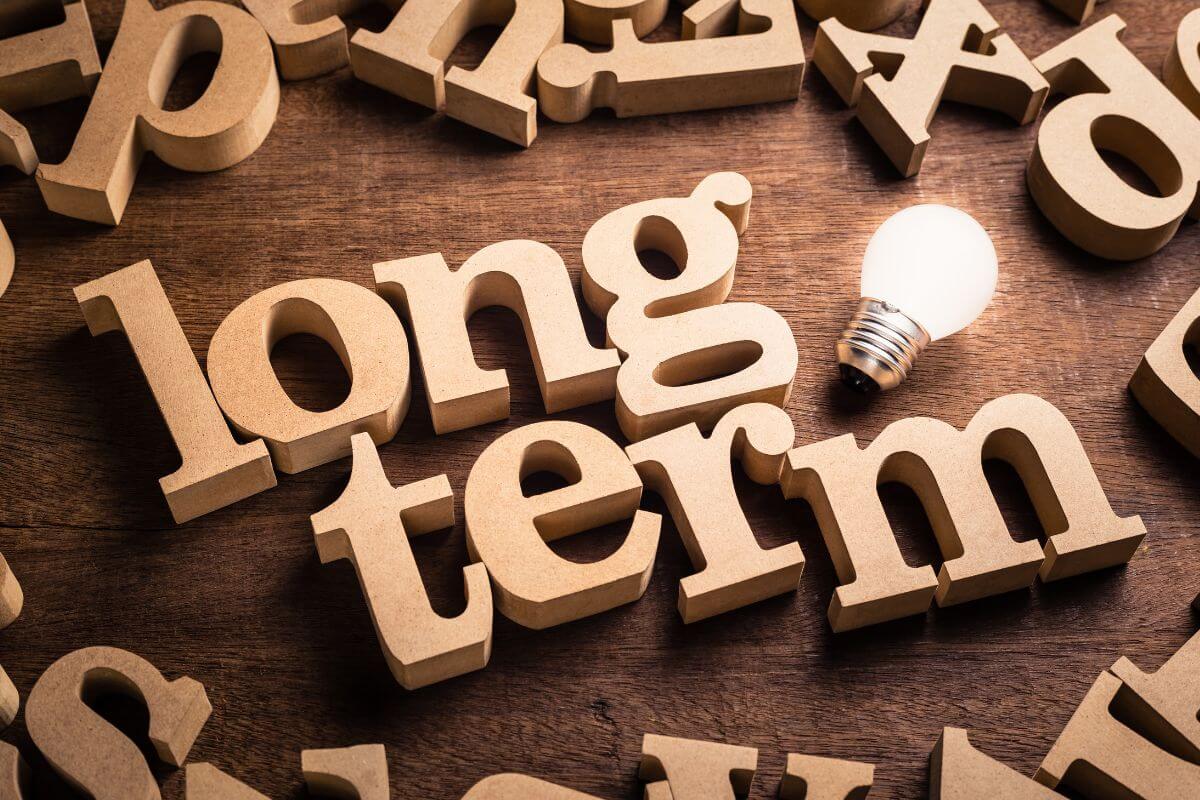 The picture tells about wooden letters and a bulb indicating that focusing on long-term impact can lead to meaningful change over time while still achieving financial growth.