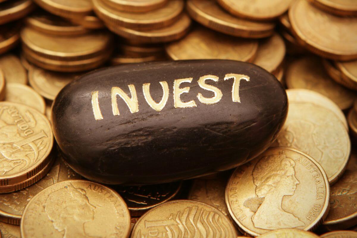The photo shows coins and a black stone with a note which means to explore the countless ways to invest money that balances smart financial growth with meaningful impact.