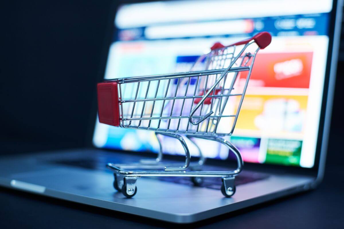 The image tells about a mini cart in a laptop which means a debt card sufficient for online purchases can work for most, but it's important to check policies for hotels and rental cars.