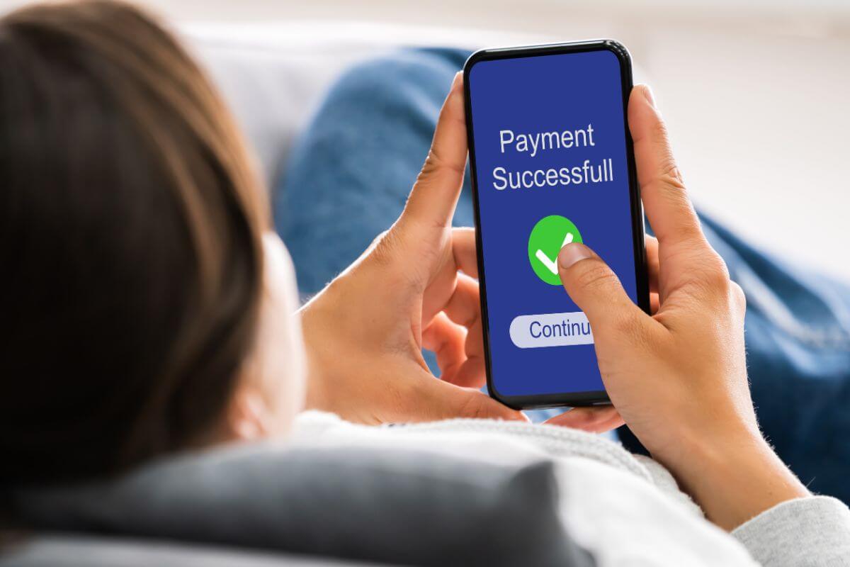 The image shows a girl using a phone with a screen display which refers to how to manage recurring payments without a credit card by setting up with debit card or directly from your bank account.