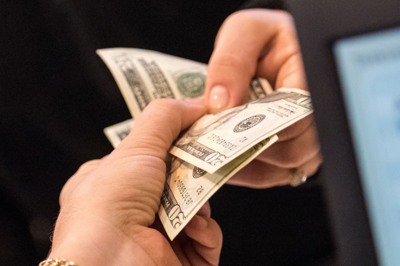 Image of a woman's hand paying cash.