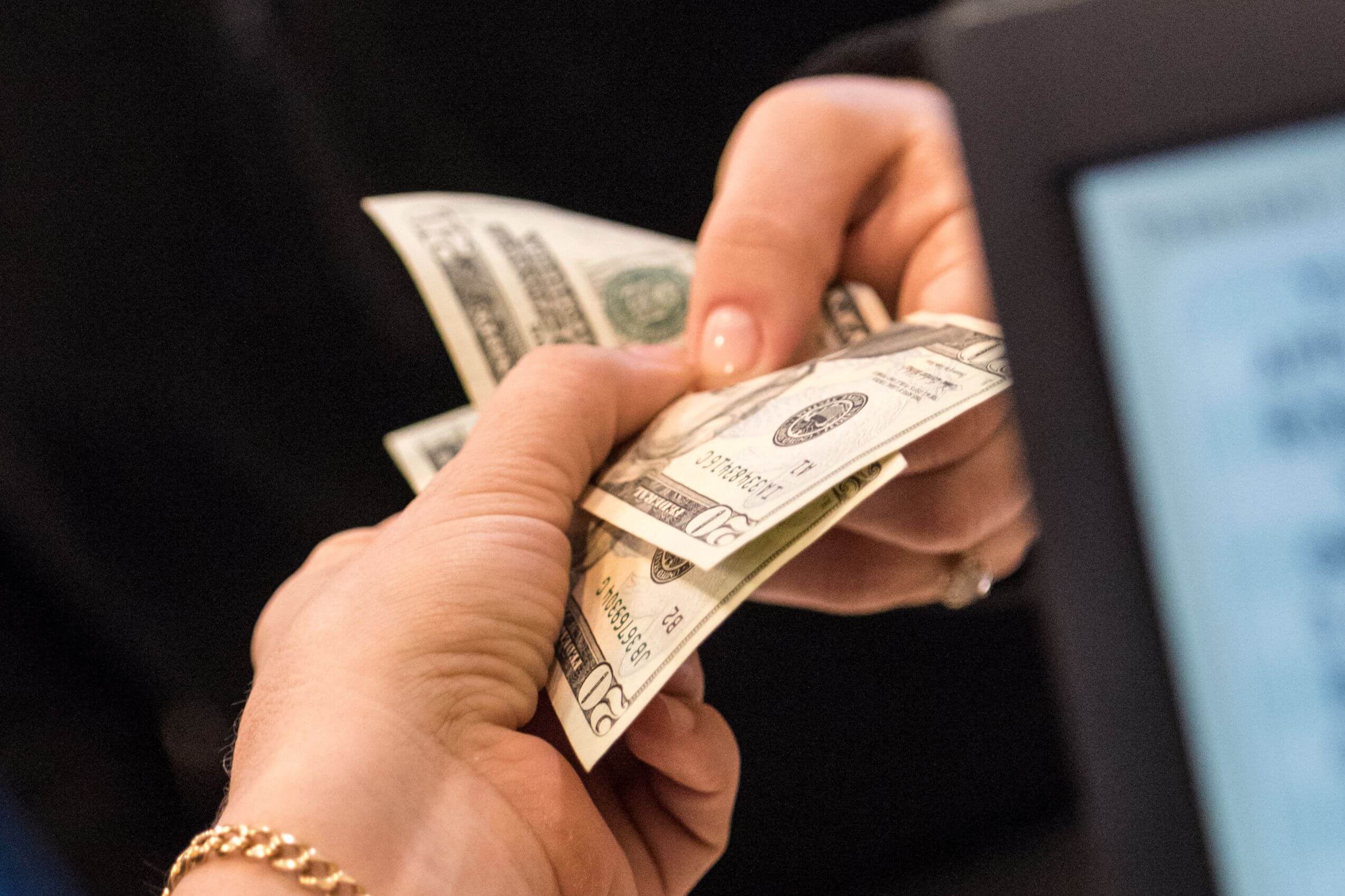 The picture tells about a customer's hand handing her dollar bills to the cashier referring to living below you means saving more money and helps you prepare for emergencies and long-term goals without relying on debt.