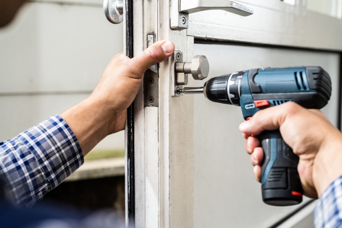 The picture shows a man's hand repairing a door knob.