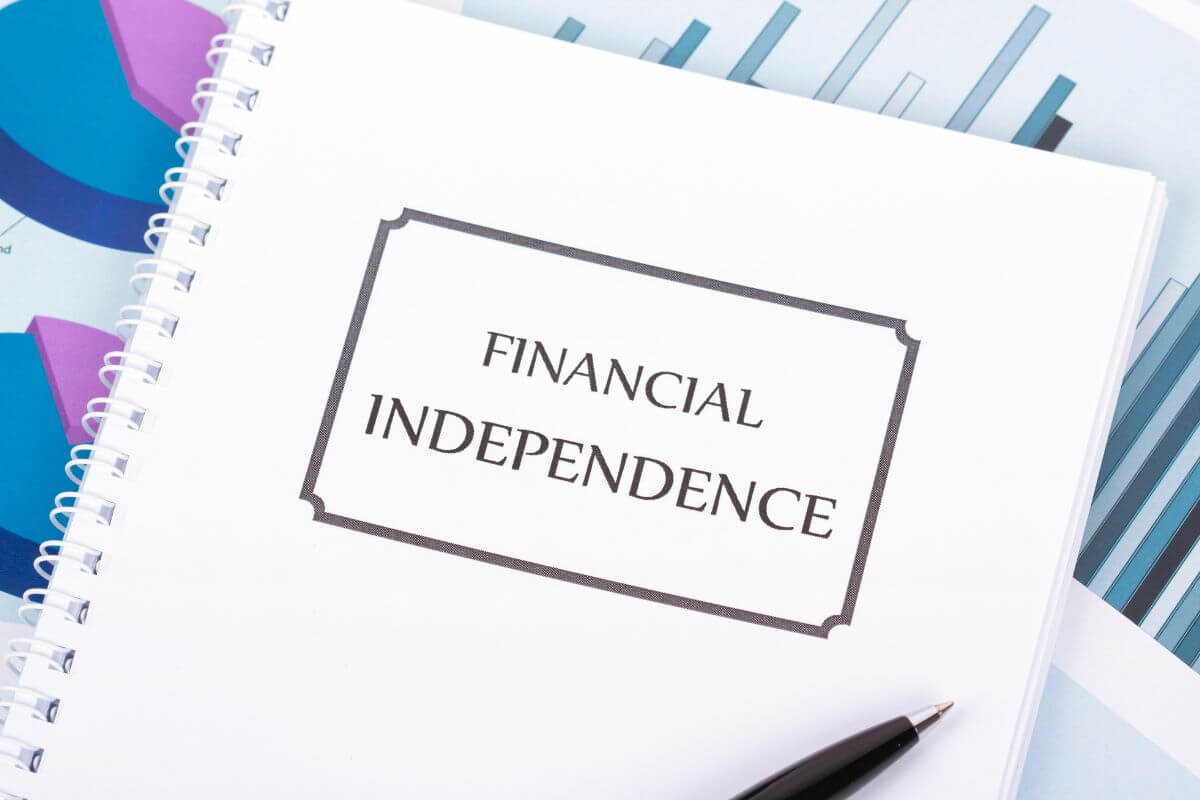 The picture of papers with graphs, a pen, and a notebook with notes indicates to time to work towards financial independence to take control of your finances today and secure a brighter future.