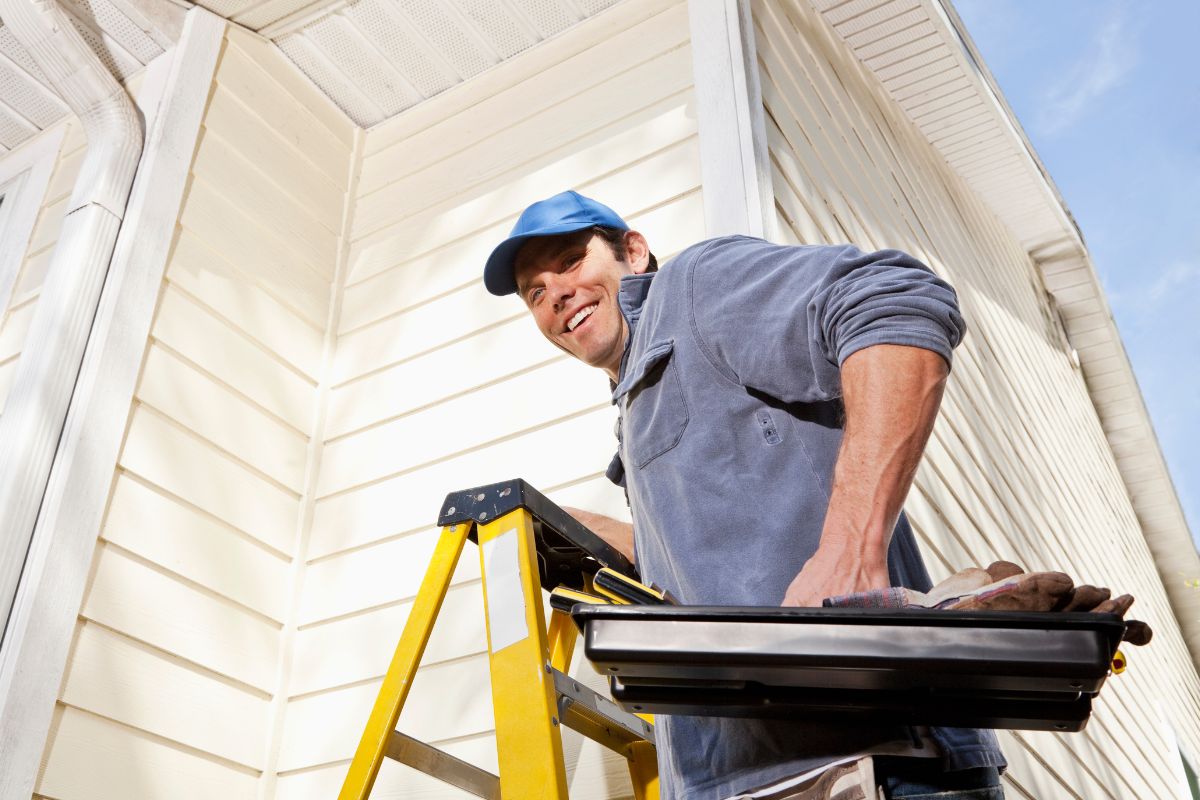 The photo shows a man repairing a house.