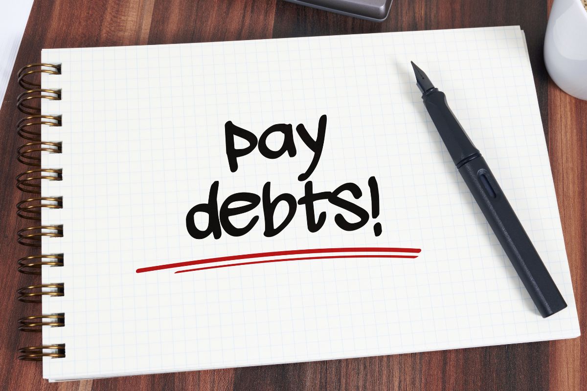 Picture of a notebook with pay debts wording.