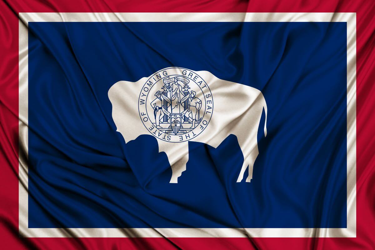 The image shows a Wyoming state flag which is one of the best states for retirees looking to save money and protect their wealth.