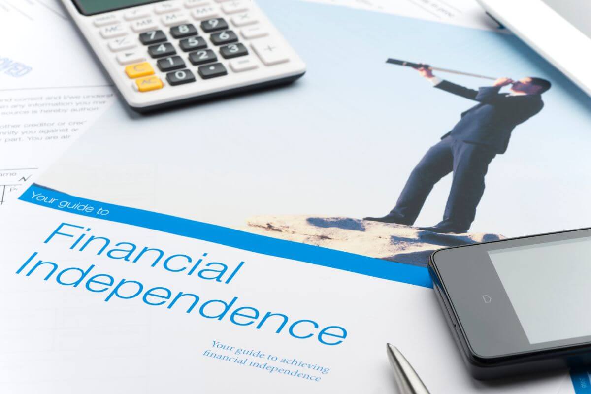 The image tells about a calculator, a phone, papers, and a magazine with a picture and notes indicating how to figure out your FI number which is a crucial step toward taking control of your future.