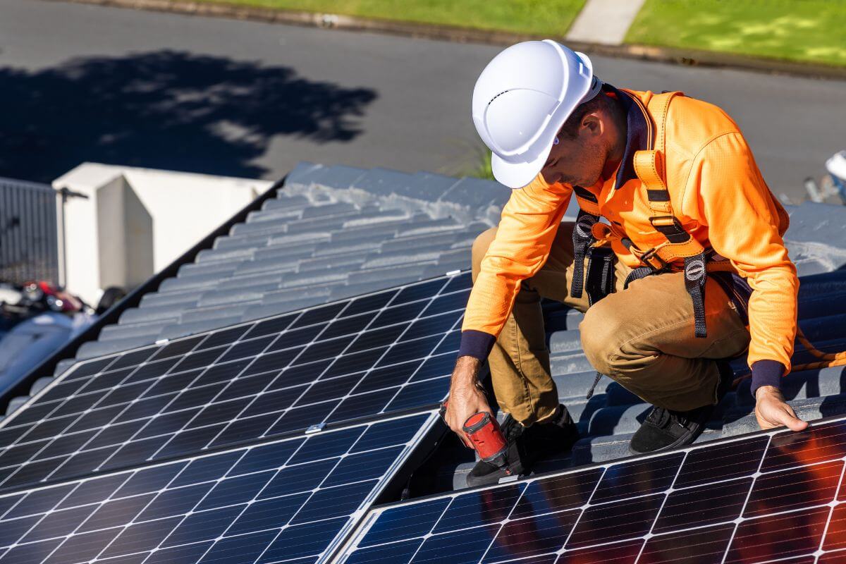 The picture of a solar panel installer with a safety helmet and a tool on the roof refers to how they make over $50 an hour while contributing a clean energy.