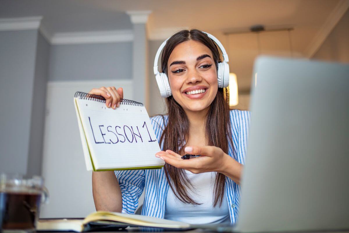 The picture of a notebook and a girl holding a notebook and pointing it while looking at the laptop that online tutors earn over  $50 an hour by teaching subjects, and it's perfect for those who enjoy teaching and want to earn a high income.