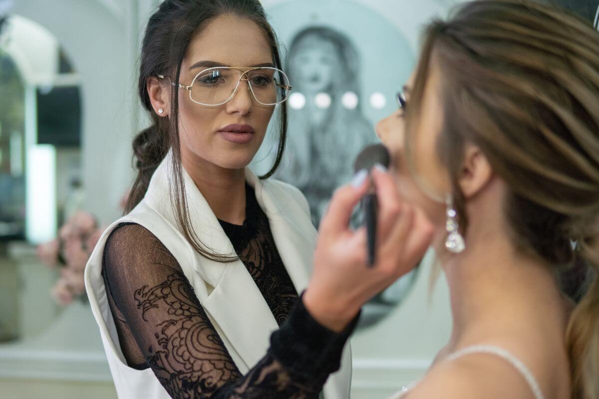 The photo tells about a makeup artist glamming the bride and earning over $50 an hour by helping clients look their best for events and more, a great way to turn artistry into a profitable and rewarding career.