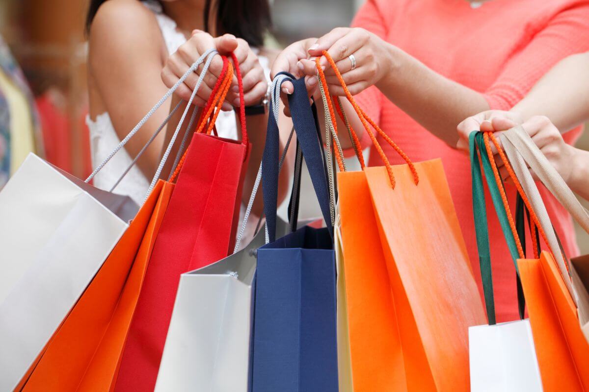 The picture shows a group of people carrying shopping bags together which means avoiding impulse purchases and overspending helps you focus on long-term priorities rather than short-term temptations.