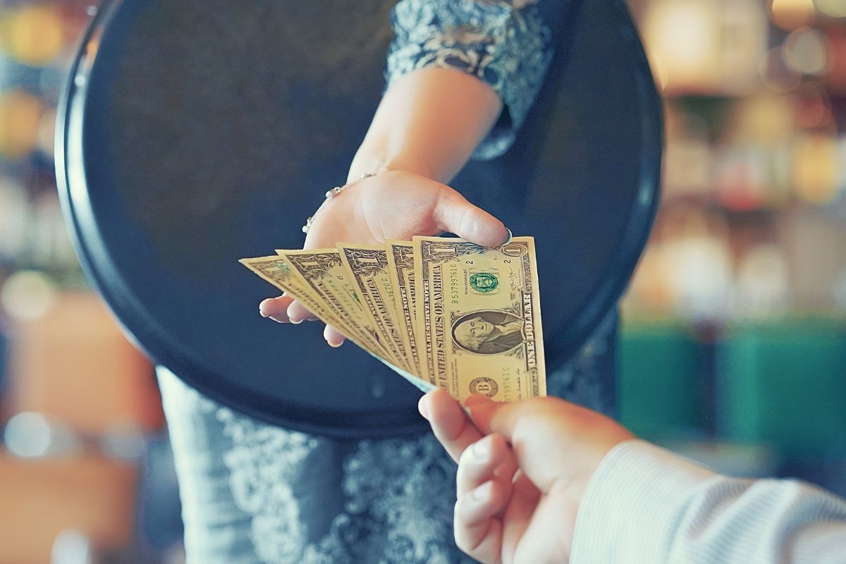 The picture shows a customer giving a waiter some tips.