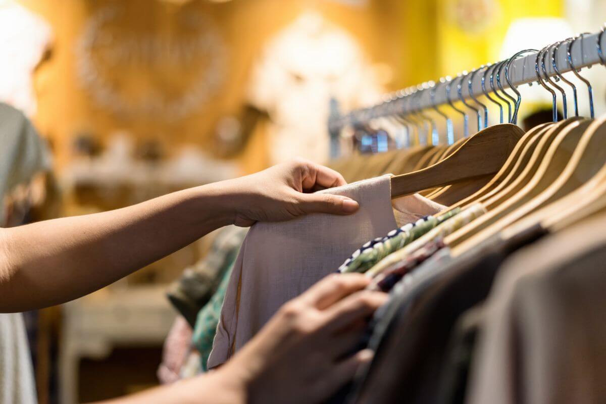 The photo shows a girl hand-picking clothes at a thrift store referring to being patient and taking your time browsing, which will help you spot the hidden gems.