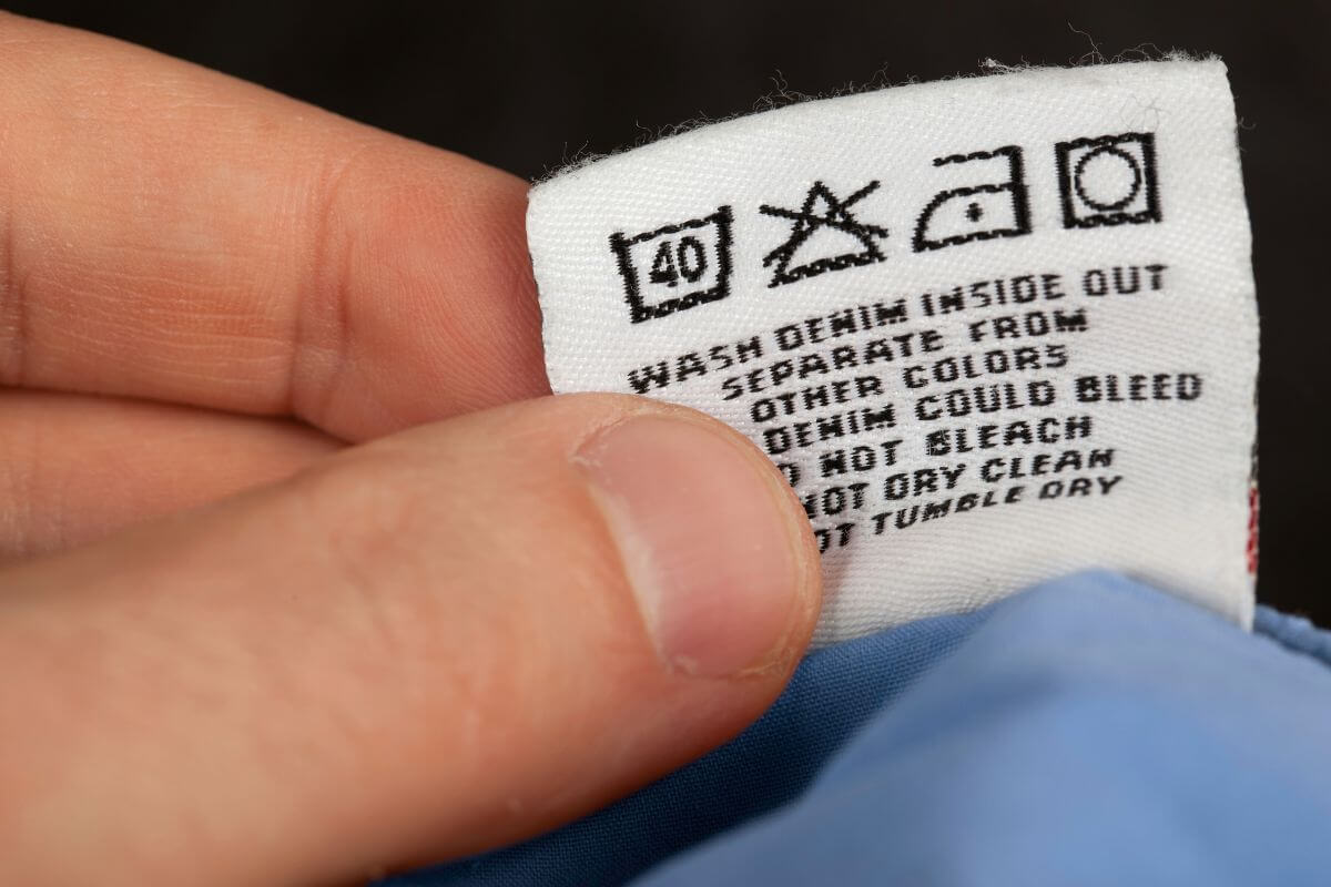 The picture tells about a man's hand checking the labels for high-end brands of a clothe that can turn a regular trip into a money-saving opportunity.