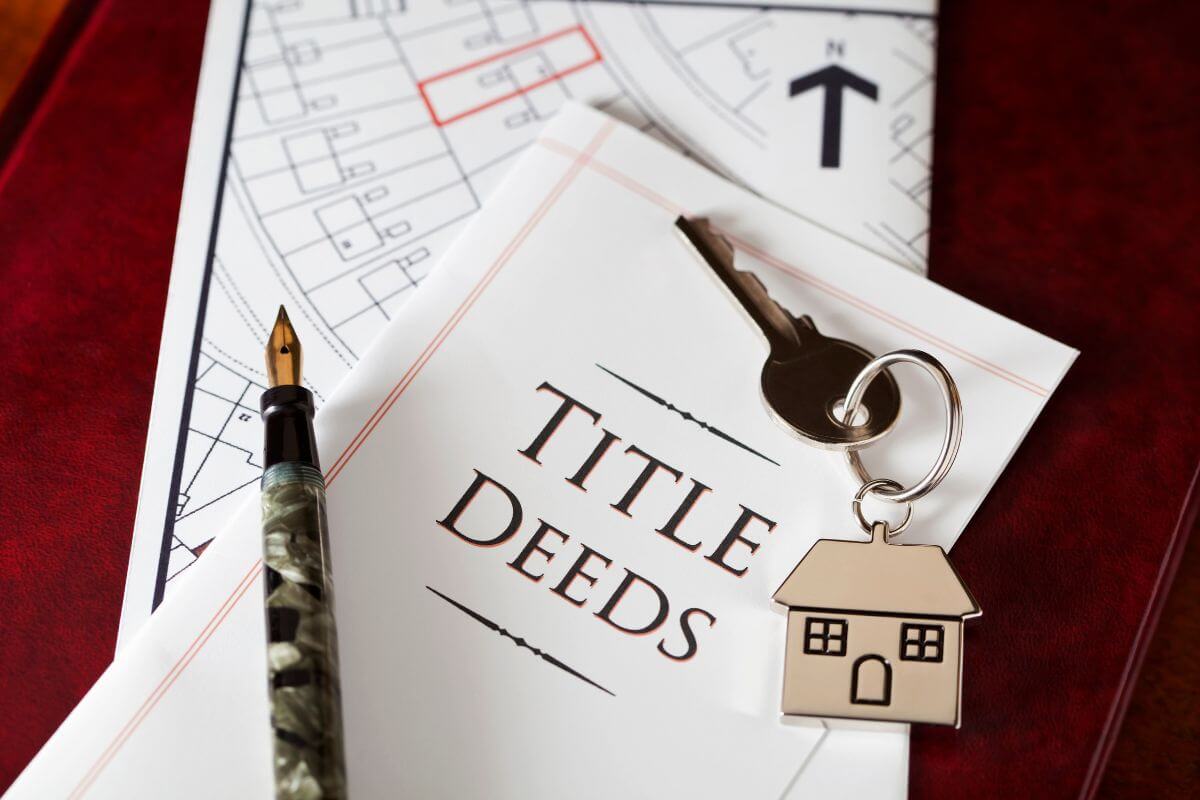 The image shows a house map, a keychain with a house figure, a pen, and a piece of paper with notes referring to jointly title property with rights of survivorship are a helpful way to avoid probate and automatically pass to the surviving owner.