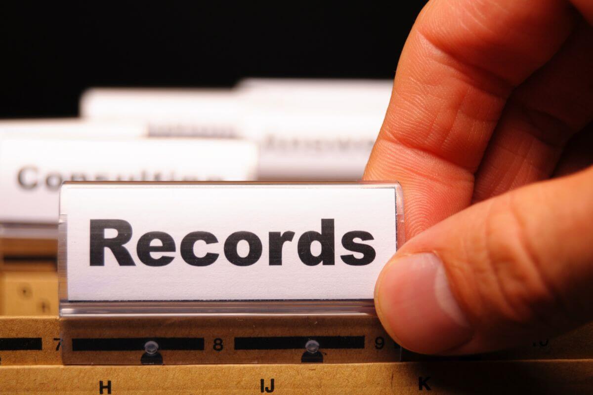 The image shows a man's hand picking a brown envelope with a tag referring to keeping detailed records of assets and ownership can help prevent disputes and ensure that your wished are carried out properly.