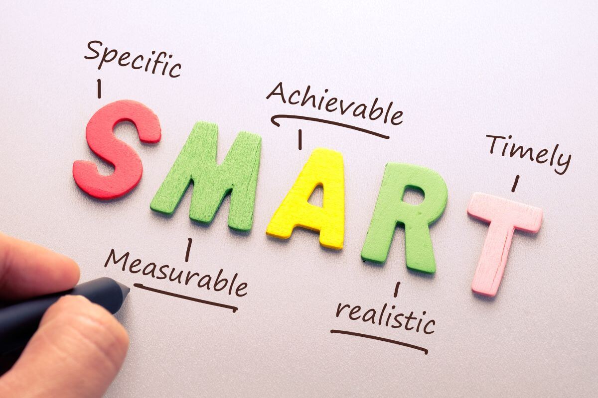 The image shows a piece of paper with letters and meaning, and a man's hand holding a pen referring to the focus on these smart financial moves which help to make smart choices now for a better future.