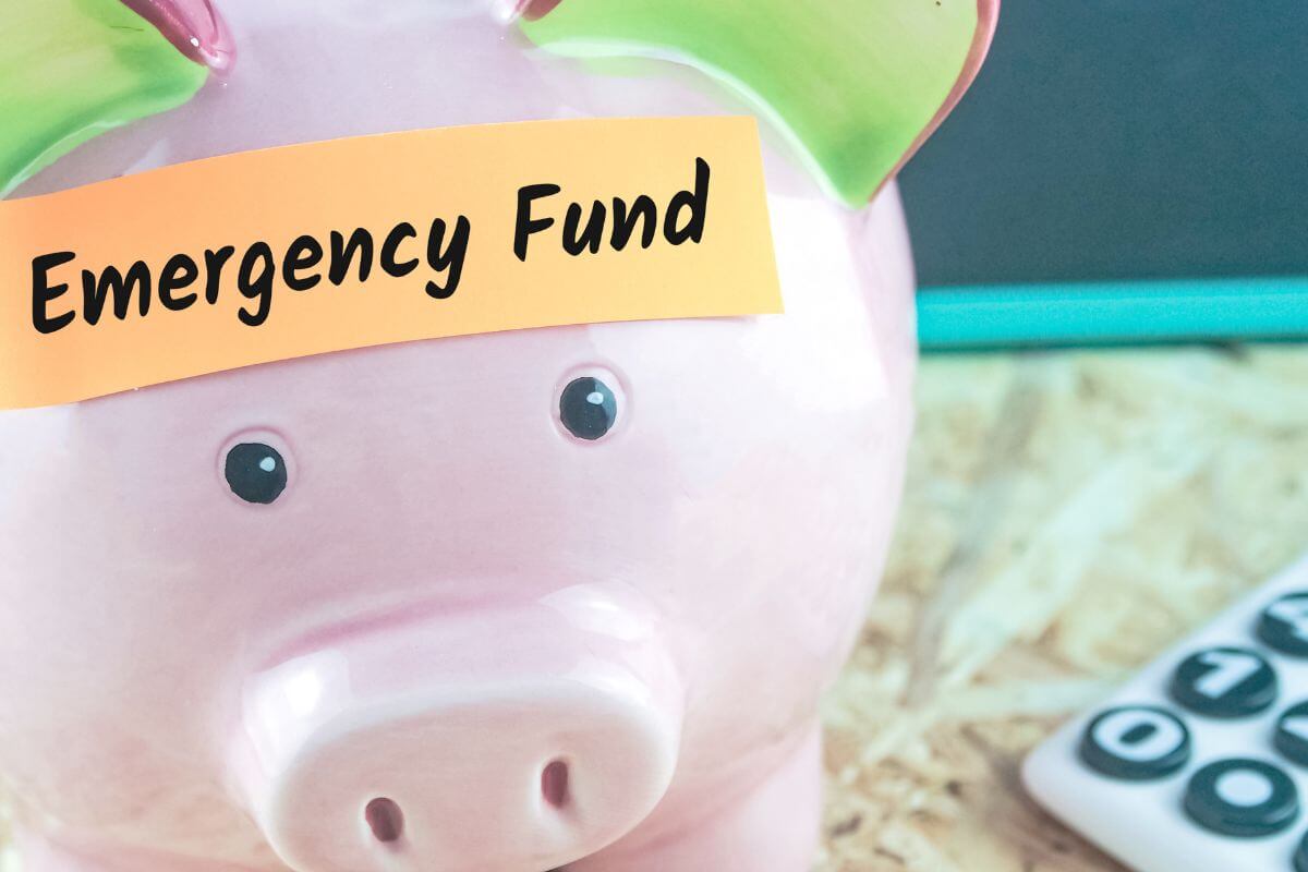 The picture shows a calculator and a piggy bank with notes indicating to focus on building an emergency fund to reduce financial stress and keep you from dipping into retirement savings early.