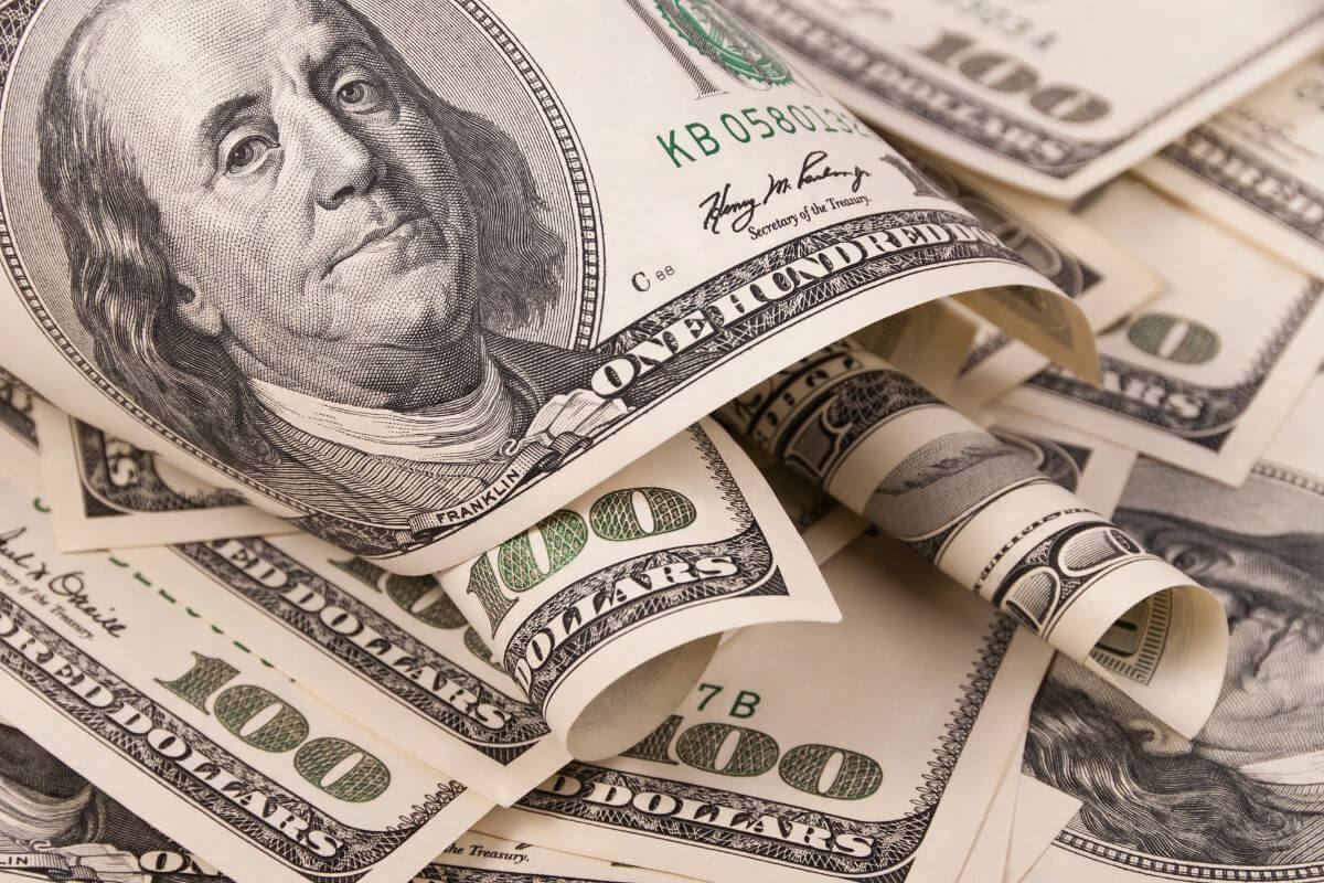 The picture shows dollar bills referring to a positive net worth means you own more than you owe and regularly tracking it helps you stay on top of your progress.