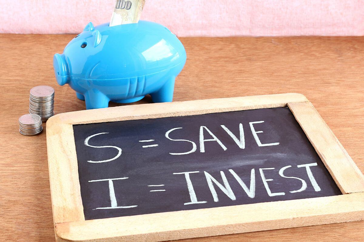The image shows stock coins, a piggy bank with a dollar bill, and a blackboard with notes referring to minimizing risk by diversifying where you save or invest helps protect your money.