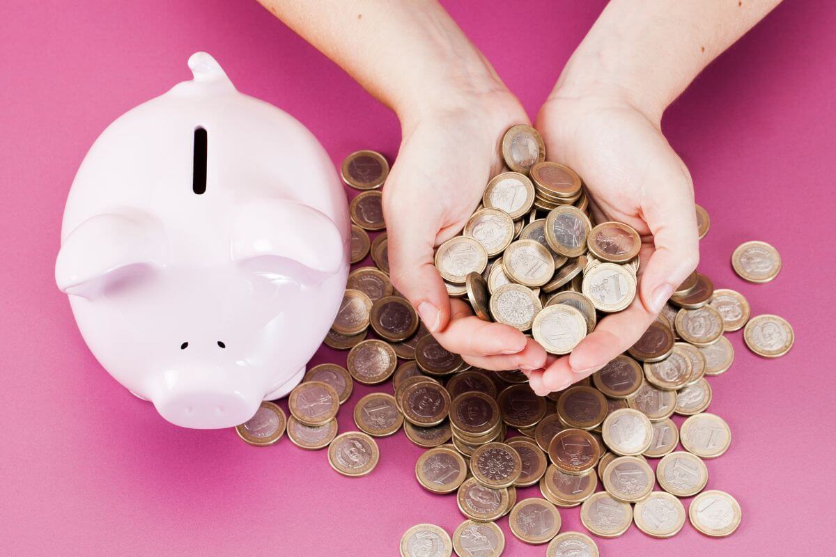 The picture of a piggy bank and a girl's hand holding coins means that staying disciplined helps you reach your goals over time.